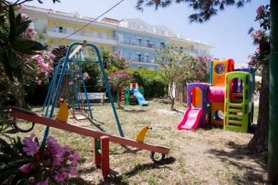a colorful playground with a swing , slide , and other play equipment in a park - like setting at Hotel Summery