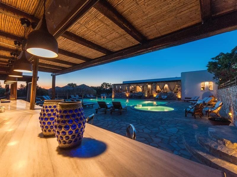 a wooden deck with a pool and a swimming pool , surrounded by chairs and a dining table at Parosland Hotel