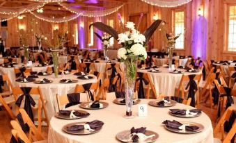 a large dining room with multiple round tables set for a formal event , each table adorned with a centerpiece of flowers at The Avalon, Durg