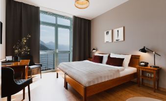 a large bed with white linens is in a room with a window overlooking the mountains at Hotel Esplanade