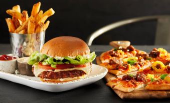 a burger , fries , and a slice of pizza are displayed on a table next to a glass at Courtyard Ontario Rancho Cucamonga