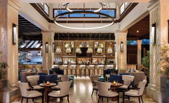 a luxurious bar with marble walls , wooden ceiling beams , and large windows , as well as comfortable seating arrangements and a menu board at Zemi Beach House, LXR Hotels & Resorts