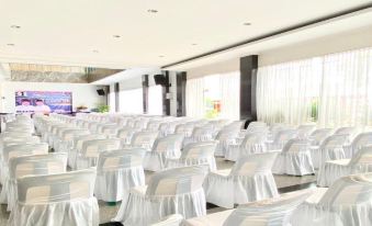 a large , empty conference room with rows of white chairs and tables set up for a meeting or event at Hotel Prima Indah