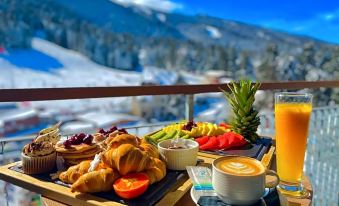 a breakfast table with a variety of food and drinks , including croissants , fruit , juice , and coffee at Rila Hotel Borovets