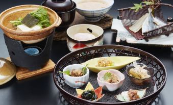 a dining table with a variety of food items , including sushi , soup , and other dishes at Hakugei