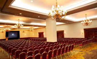 a large , well - lit conference room with rows of red chairs and a chandelier hanging from the ceiling at JW Marriott Hotel Caracas