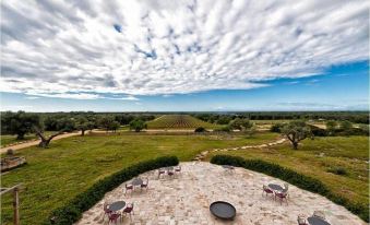 a patio area with a fire pit and chairs is surrounded by green grass and trees at Masseria le Fabriche