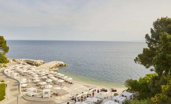a beach scene with umbrellas , chairs , and people is shown from a high vantage point at Kempinski Hotel Adriatic Istria Croatia