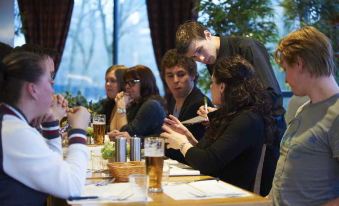 a group of people gathered around a dining table in a restaurant , engaged in conversation and enjoying their meal at Bastion Hotel Bussum Hilversum