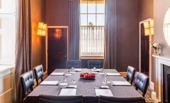 a dining room with a long table set for a meal , surrounded by chairs and a window at The Langley, a Luxury Collection Hotel, Buckinghamshire