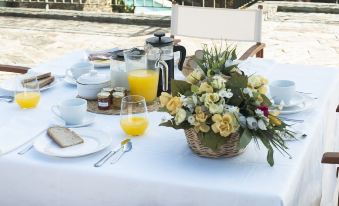 a table is set with a white tablecloth , vases of flowers , and a glass of orange juice at Quinta Da Marka