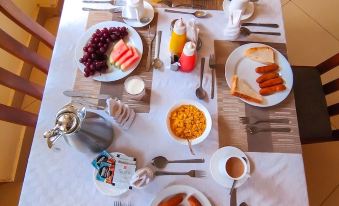 a dining table set with a variety of breakfast items , including eggs , toast , fruit , and coffee at Calabash Hotel