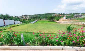 a beautiful view of a green field with pink flowers , surrounded by houses and trees , under a clear blue sky at Royal Elmount Hotel