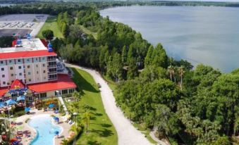 an aerial view of a resort with a large swimming pool , surrounded by trees and a lake at Legoland® Florida Resort