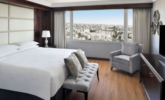 a luxurious bedroom with a large bed , a couch , and a window overlooking a city view at Amman Marriott Hotel