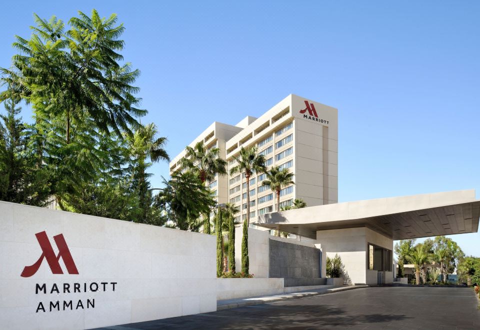 the exterior of the marriott hotel in miami , florida , with its large sign and palm trees in the background at Amman Marriott Hotel