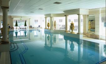 an indoor swimming pool with a large rectangular shape , surrounded by a white tiled floor at The Keadeen Hotel