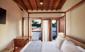 a cozy bedroom with a wooden bed , white bedding , and a view of a balcony outside at San Rafael