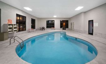 an indoor swimming pool with a white tiled floor , surrounded by black windows and balconies at La Quinta Inn & Suites by Wyndham Knoxville North I-75