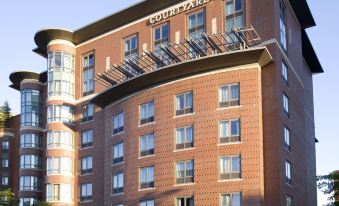 "a brick hotel building with an open balcony and a sign that reads "" courtyard by marriott .""." at Courtyard by Marriott Boston Brookline