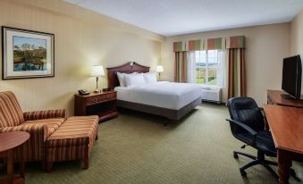 a hotel room with a large bed , a chair , and a laptop on the desk at DoubleTree by Hilton Front Royal Blue Ridge Shadows