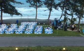 a well - arranged outdoor wedding reception with tables covered in blue and white tablecloths , chairs , and a band playing at the stage at Greenseaviewresort Bangsaphan