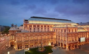 a large , ornate building with a domed roof is illuminated at night in a city setting at Hotel Bristol, a Luxury Collection Hotel, Vienna