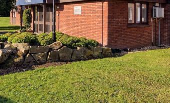 a brick house surrounded by grass and trees , with a grassy area in front of it at Travelodge Sleaford