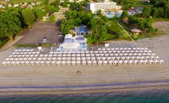 aerial view of a sandy beach with rows of white lounge chairs lining the shore at Olympian Bay Grand Resort