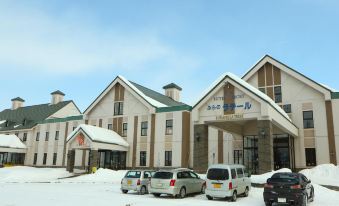 "a large building with a sign that reads "" hi - speed hotels "" is surrounded by several cars" at Furano la Terre