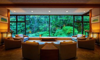 a room with a large window overlooking a lush green forest , creating a serene and tranquil atmosphere at Harataki