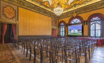 a large , ornate room with a stage and rows of chairs facing a large screen at Hotel Villa Cornér Della Regina