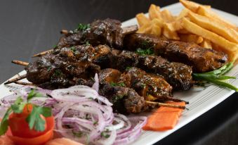 a plate of food , including meat and vegetables , with french fries and onions , is presented on a table at Ras Al Jinz Turtle Reserve