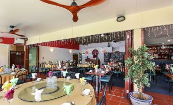 a restaurant with a large dining table and chairs , as well as a fan hanging from the ceiling at Lennox Beach Resort