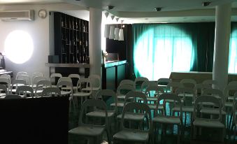 a conference room with white chairs arranged in rows , and a television mounted on the wall at Hotel la Lucertola