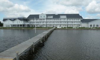 a large white hotel building situated on the edge of a body of water , with a pier extending into the water at Lakeside Resort & Conference Center