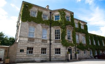 a stone building with ivy growing on its facade , situated on a city street under a blue sky at Best Western Plus Aston Hall Hotel