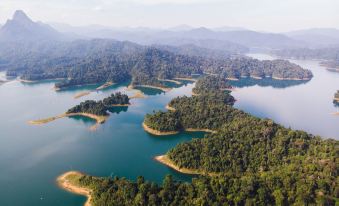 a bird 's eye view of a serene lake surrounded by lush green trees and mountains at Our Jungle House