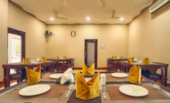 a well - lit dining room with several tables set for a meal , each table having its own yellow napkins at Hotel Empire