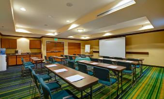 a conference room with multiple tables and chairs arranged in rows , along with a projector screen at Fairfield Inn & Suites Worcester Auburn