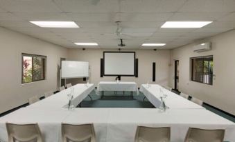 a conference room with a large table surrounded by chairs , and a projector screen on the wall at Discovery Parks - Ballina