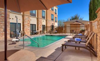 an outdoor pool surrounded by lounge chairs and umbrellas , providing a relaxing atmosphere for guests at SpringHill Suites Thatcher