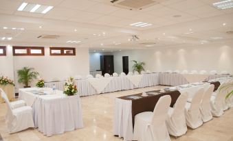 a well - organized event space with white tables and chairs arranged for a meeting or event at Marinaterra Hotel & Spa