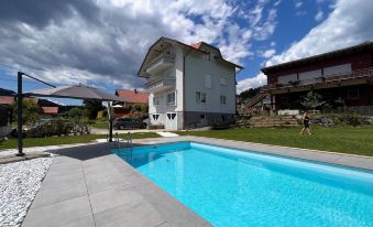 a large swimming pool is surrounded by a house with a patio and an umbrella at Frank