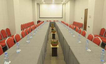 a long conference table with red chairs and a white projector screen in the background at Citrus Hotel