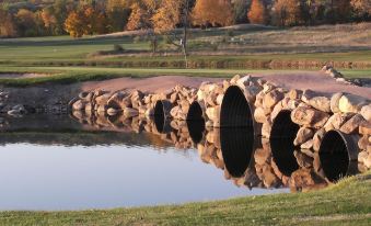 a stone bridge spanning a small body of water , surrounded by lush green trees and grass at Devil's Head Resort