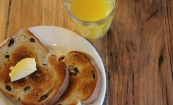 a plate of toast and a glass of orange juice are placed on a wooden table at Alexandra Place