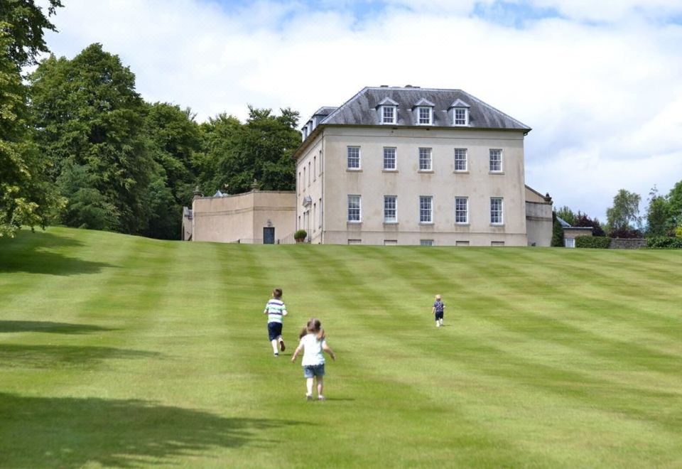 a group of children are playing on a grassy field in front of a large building at Station House Hotel Letterkenny