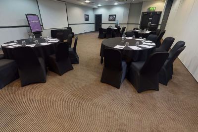 a conference room with several tables and chairs , each set with a black tablecloth and a number on the wall at Village Hotel Liverpool