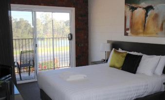 a bedroom with a large bed and white linens , next to an open door leading to a balcony at Mildura Riverview Motel